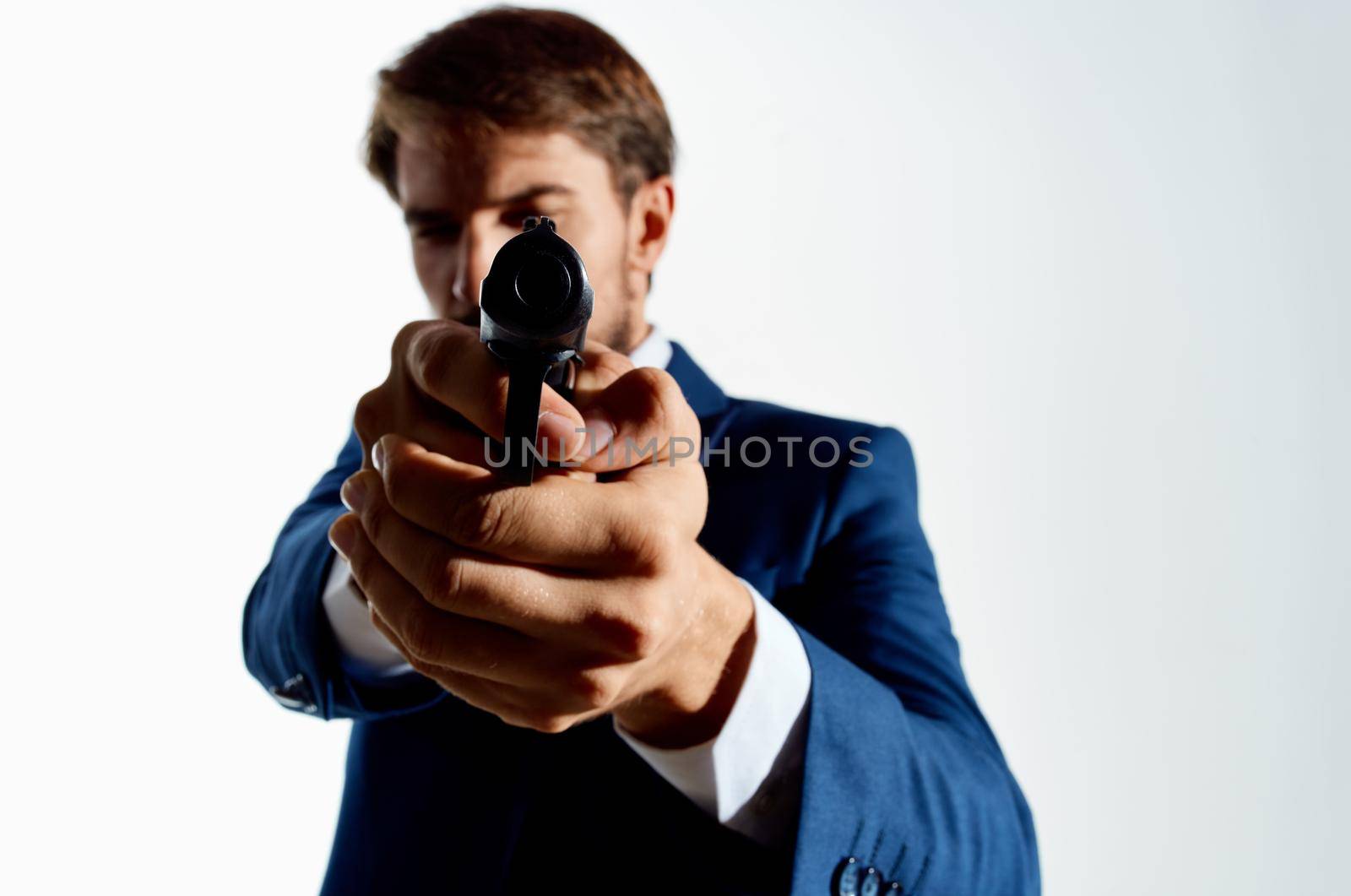 Man gun in the hands of the mafia emotions Agent light background. High quality photo