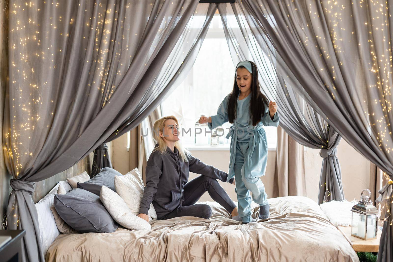 happy mother and daughter playing in bed.