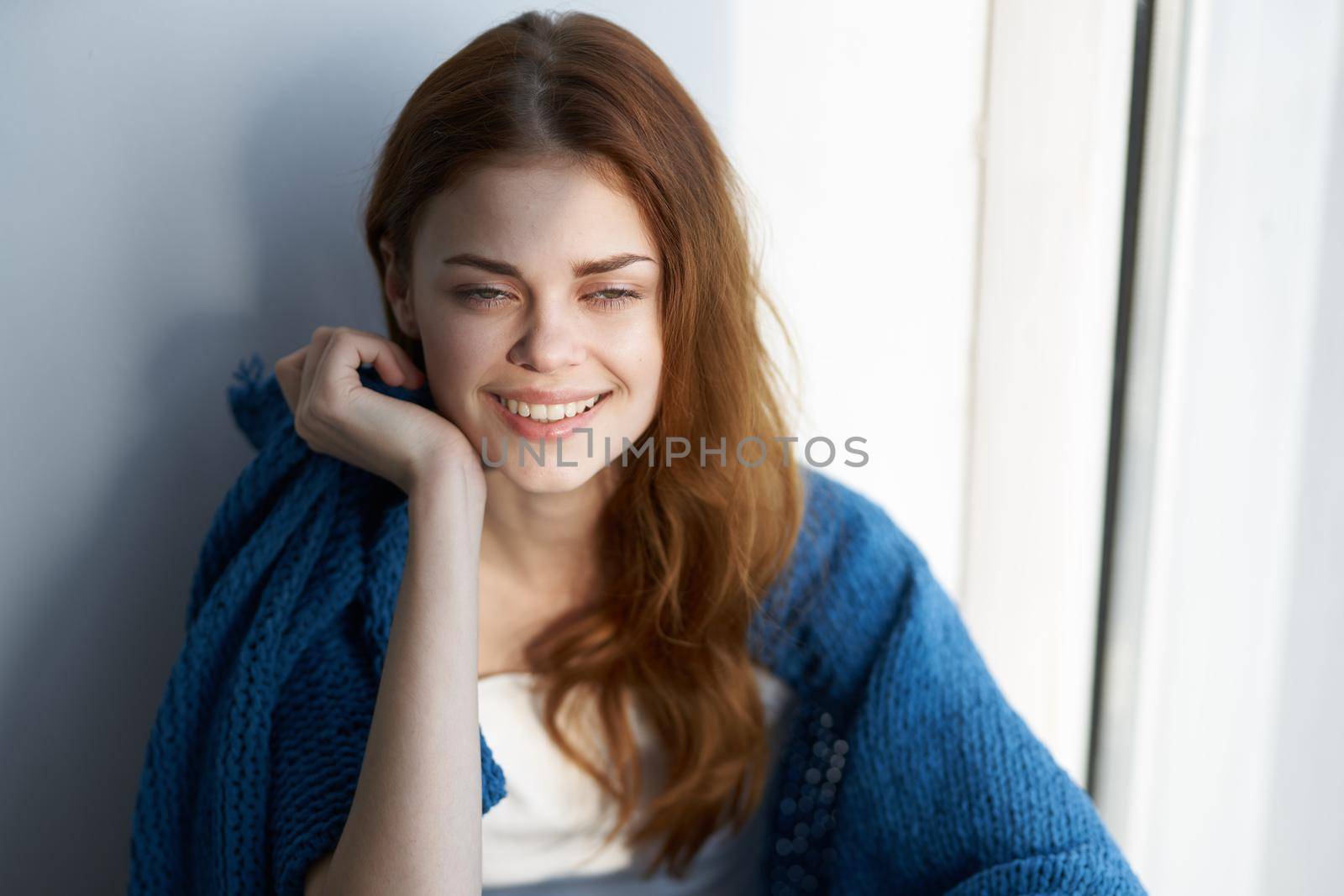 beautiful woman sitting near the window with a blue plaid. High quality photo