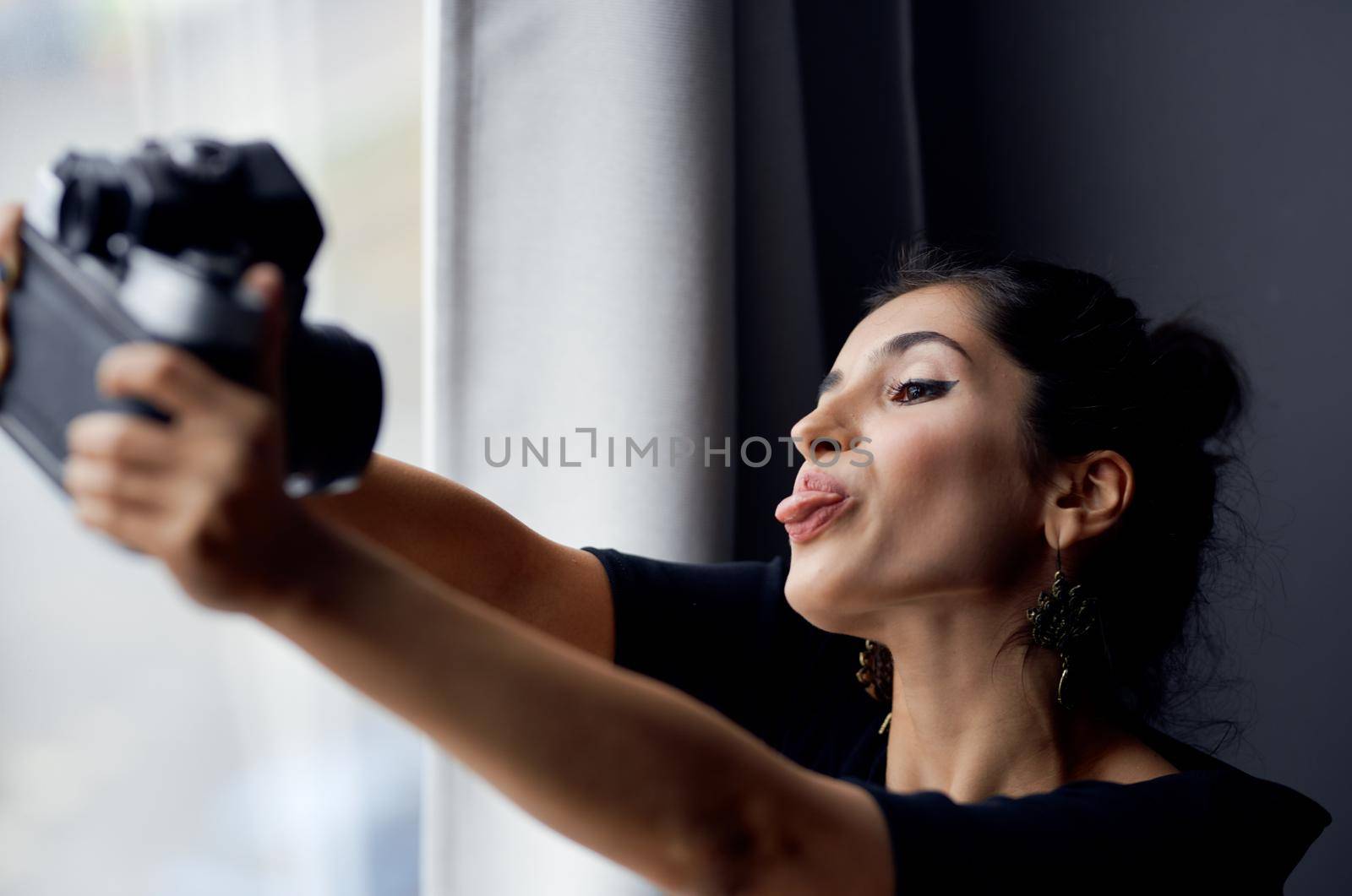 pretty woman holding a camera near the window decoration fashion lifestyle studio. High quality photo