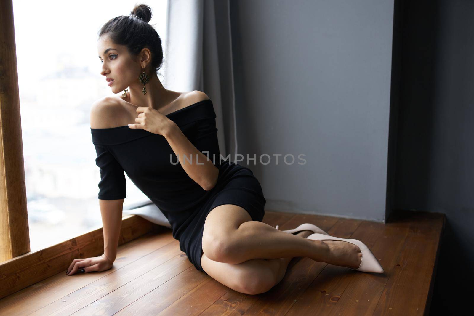 beautiful woman in a black dress near the window posing fashion model. High quality photo