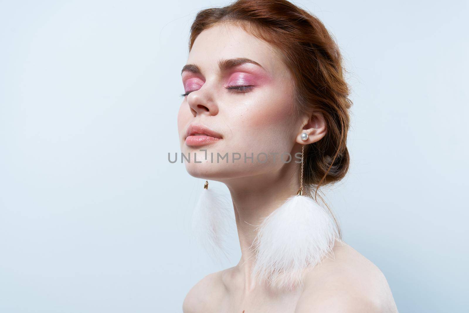 woman with bare shoulders and bright makeup jewelry fluffy earrings. High quality photo