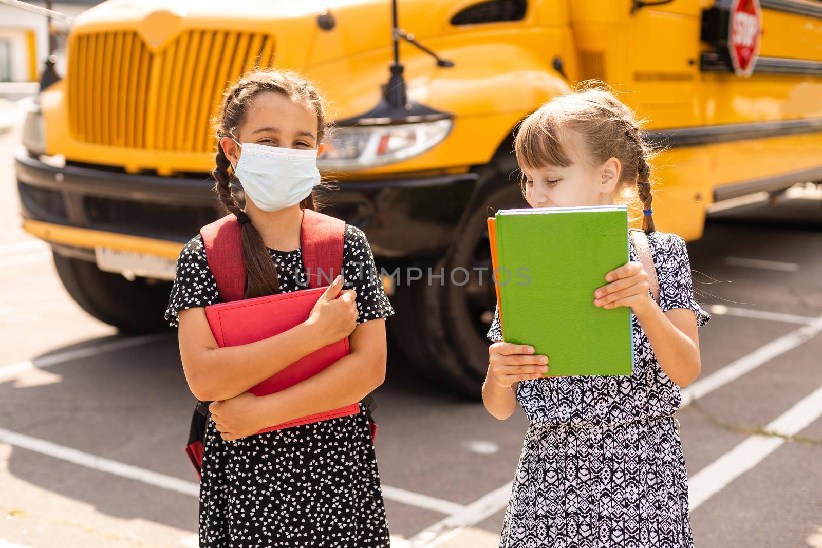 The schoolgirl puts on a mask to prevent colds and viruses. Medical concept. Back to school. Child going school after pandemic over