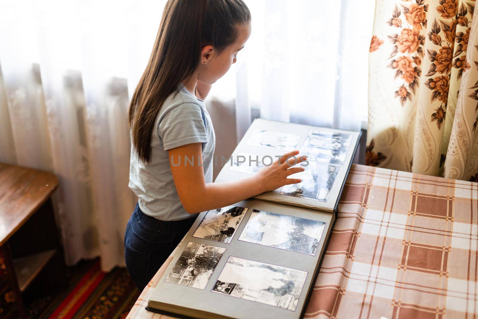 Adorable girl browsing an family album. Vintage style.