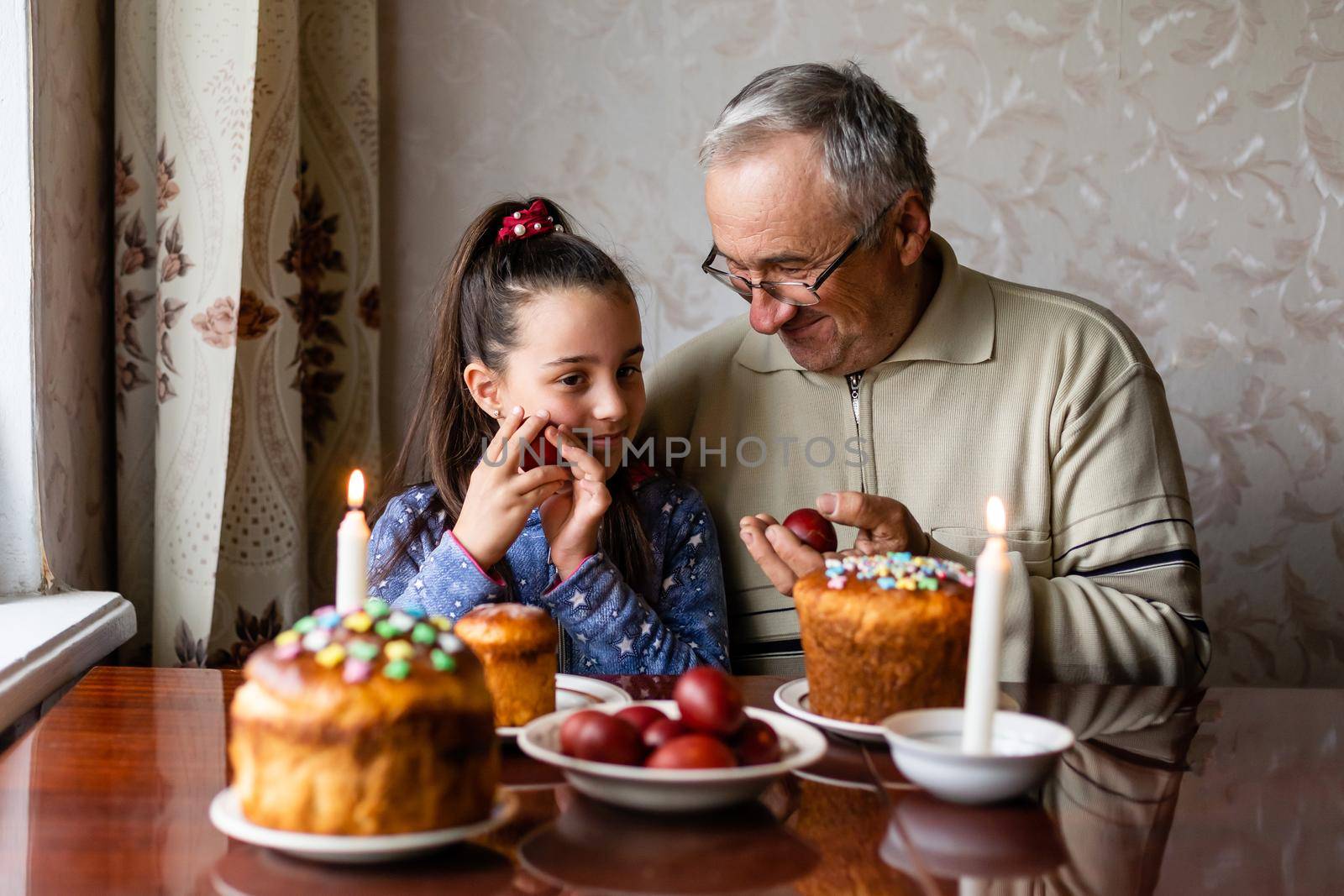grandfather and granddaughter at a festive table to celebrate Easter by Andelov13