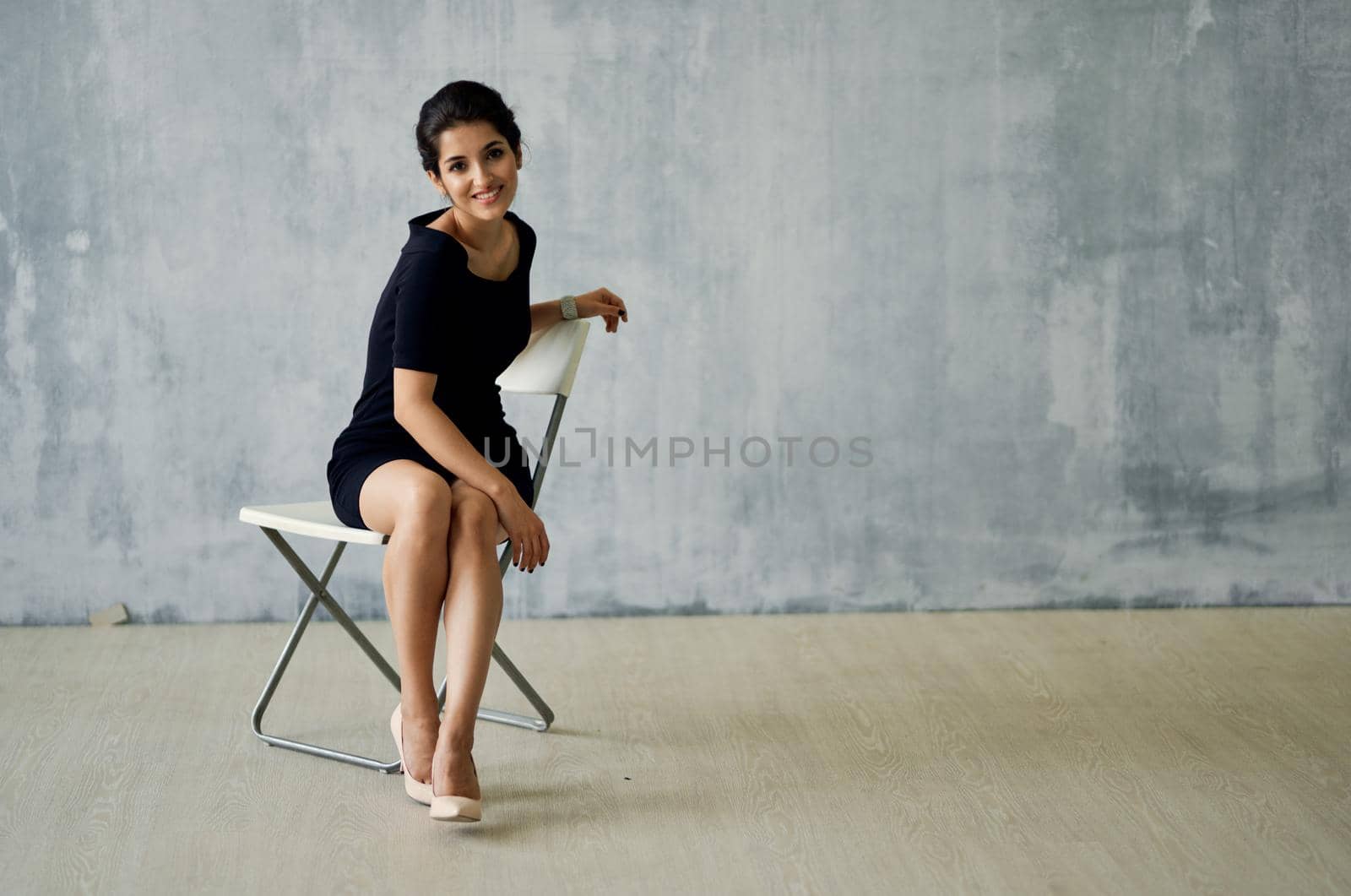 woman sitting on a chair in a black dress posing fashion luxury. High quality photo