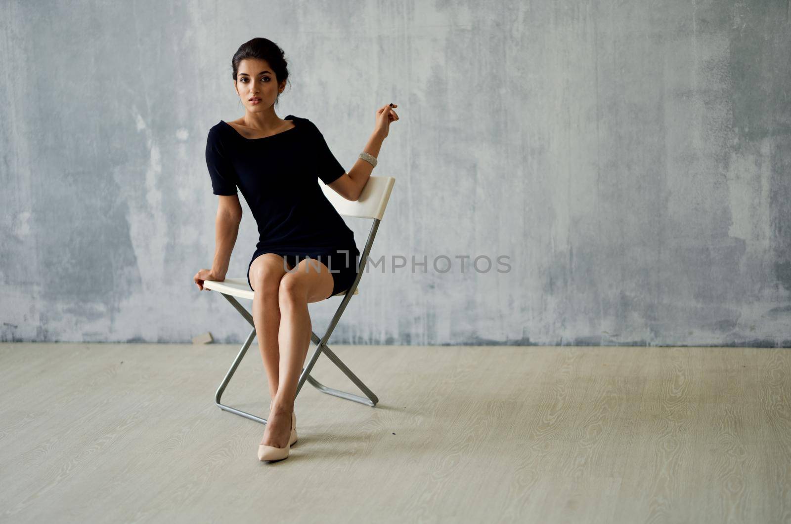 a woman in a black dress sits on a posing chair Studio Moda luxury. High quality photo