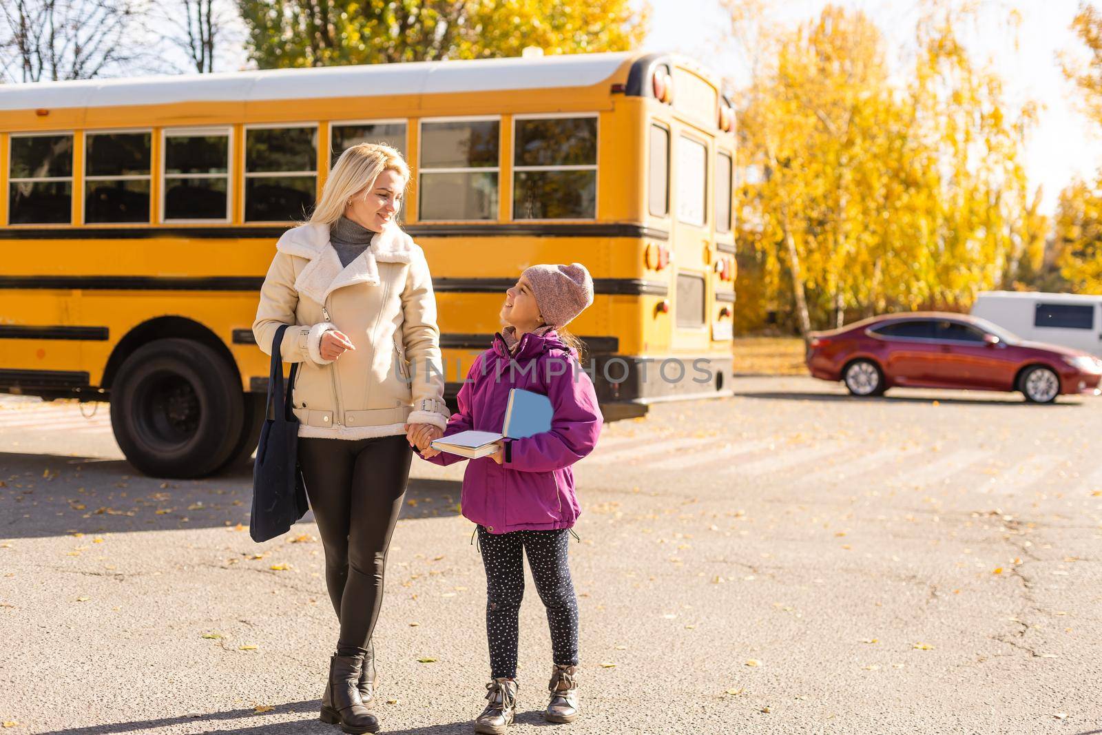 Mother walking her daughter to school bus outside the elementary school