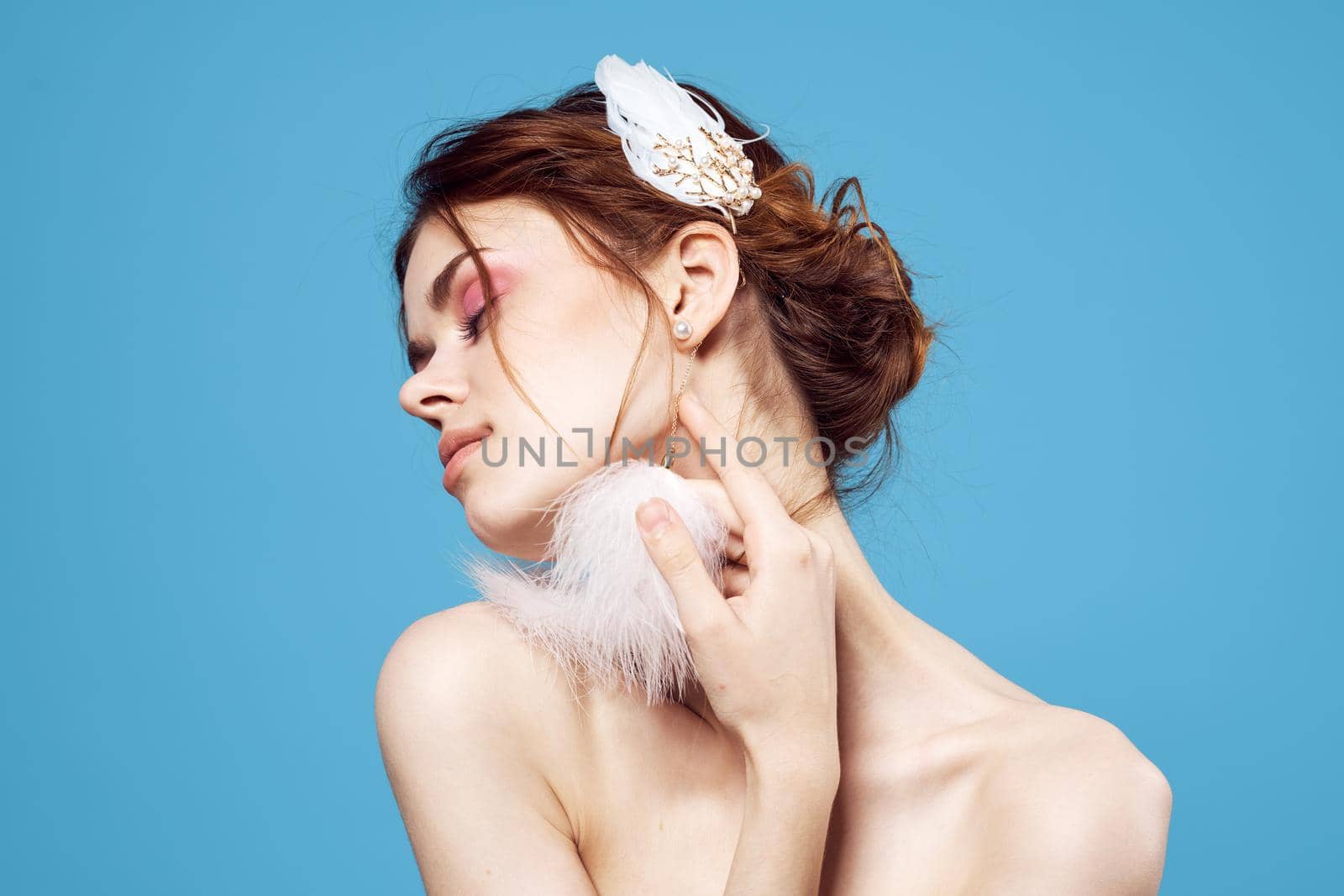 cheerful woman with bare shoulders fluffy earrings and fashion glamor blue background. High quality photo