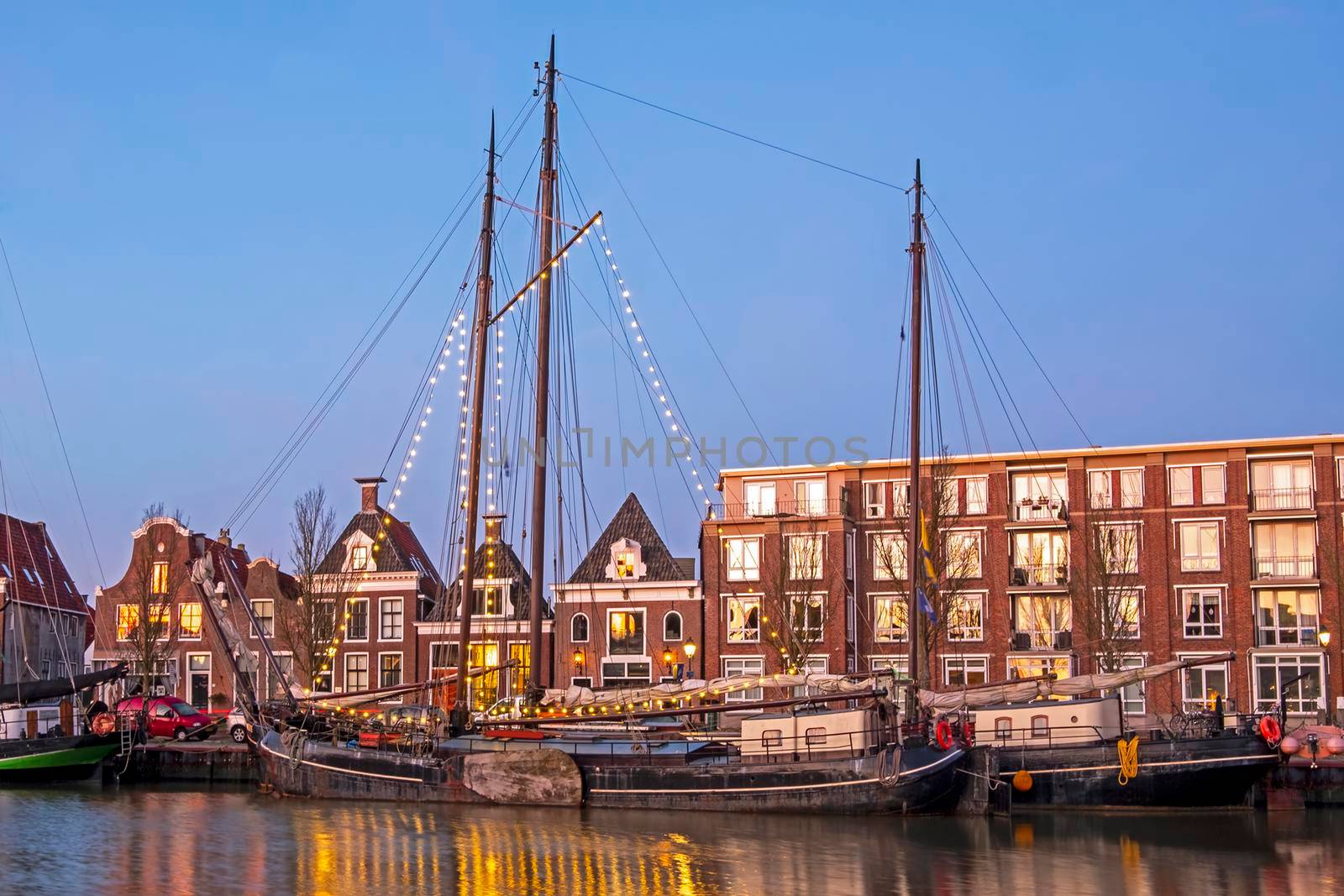 Decorated traditional sailing ship in the harbor from Harlingen in the Netherlands at sunset by devy