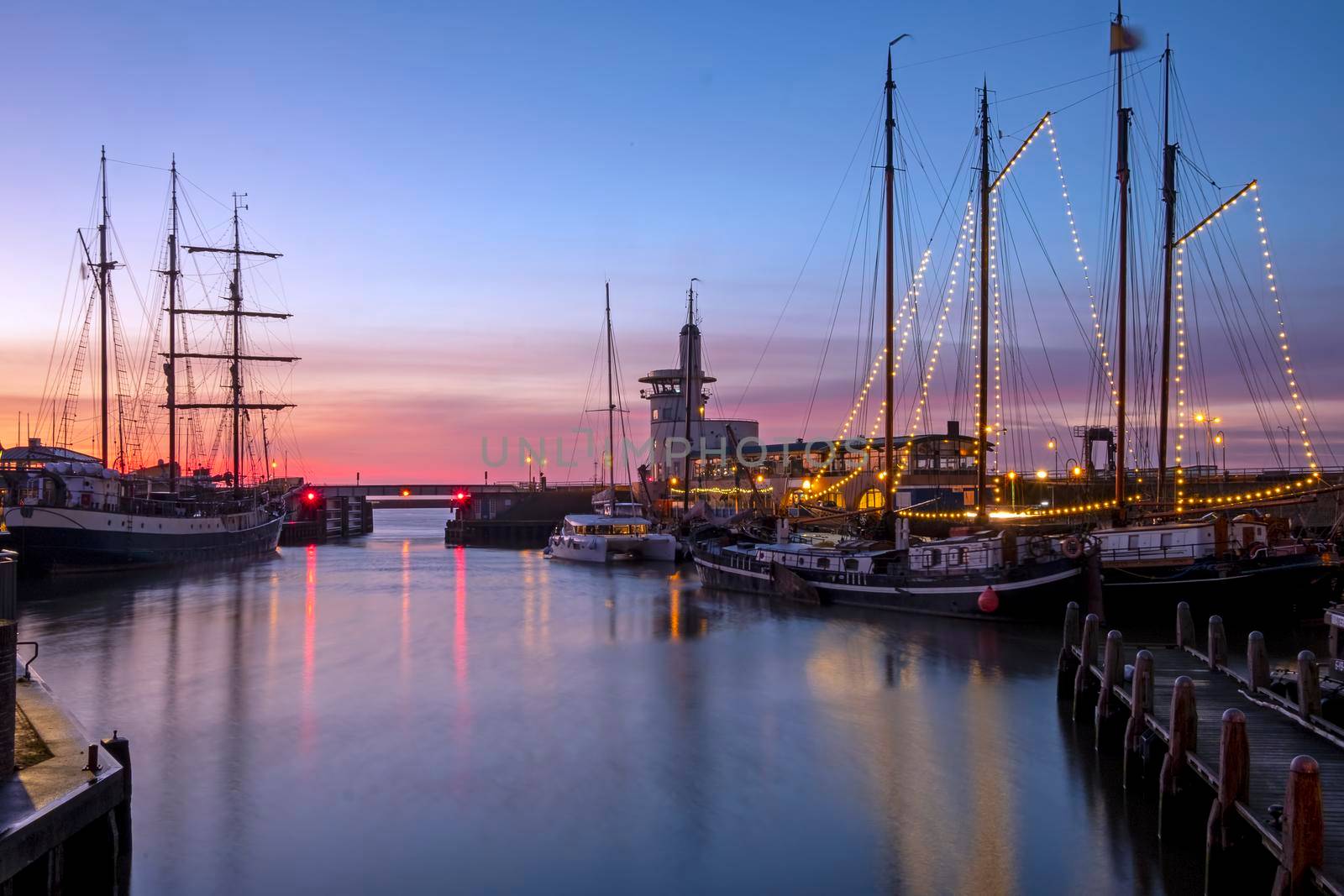 Harbor from Harlingen with decorated sailing boats in Friesland the Netherlands at sunset by devy