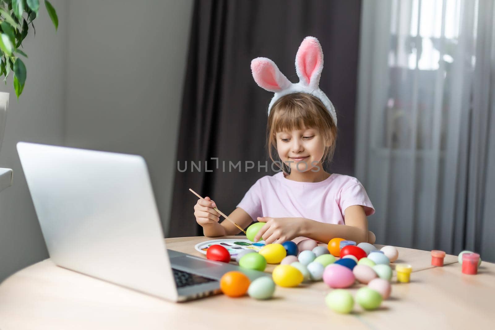 Little girl with her bunny using computer together preparing for easter.