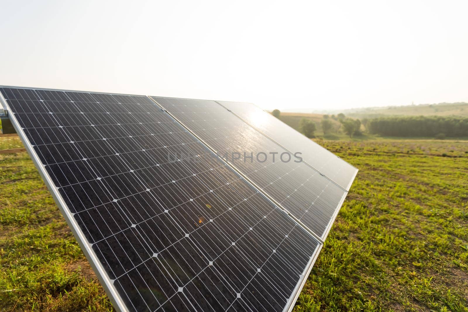 Solar panel on blue sky background. Green grass and cloudy sky. Alternative energy concept.