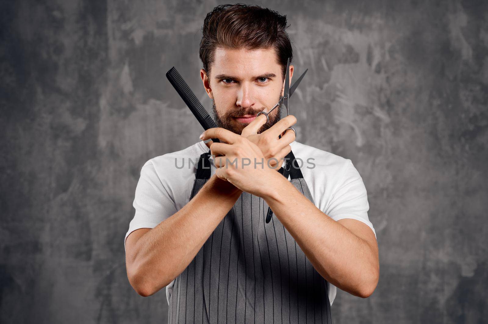 male hairdresser in an apron with a comb in his hands and scissors by SHOTPRIME