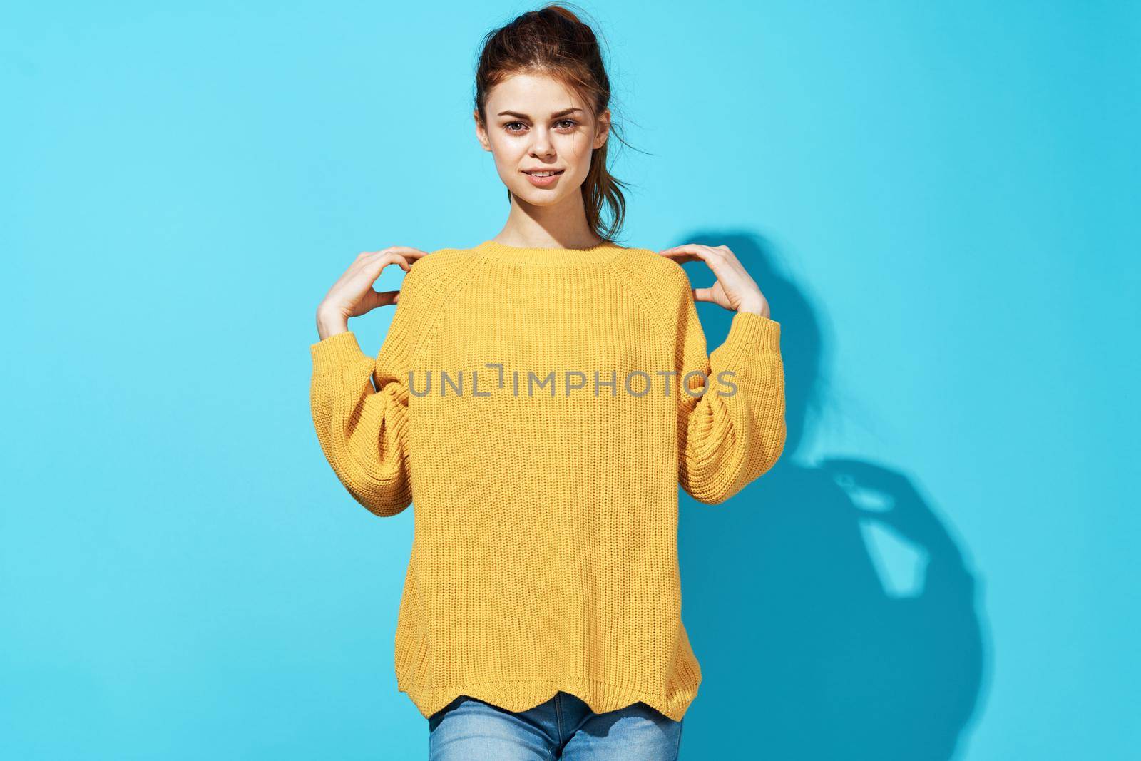 cheerful fashionable woman in yellow sweater posing fashion clothing blue background. High quality photo