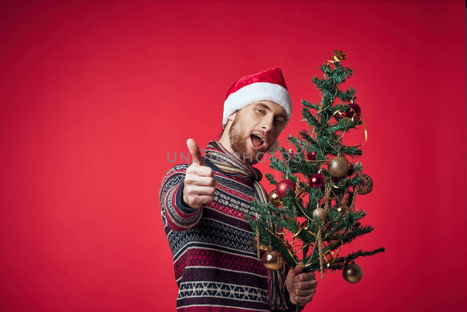 Cheerful man in a santa hat Christmas decorations holiday New Year red background. High quality photo