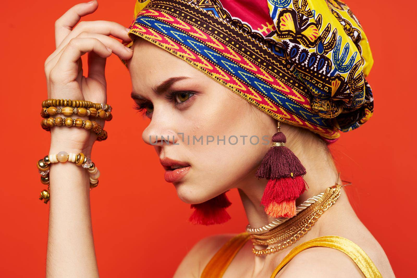 cheerful woman ethnicity multicolored headscarf makeup glamor red background. High quality photo