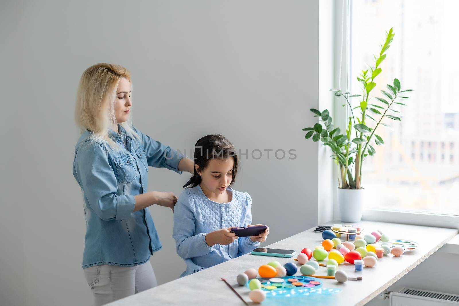 Happy family preparing for Easter. mom combing daughter by Andelov13