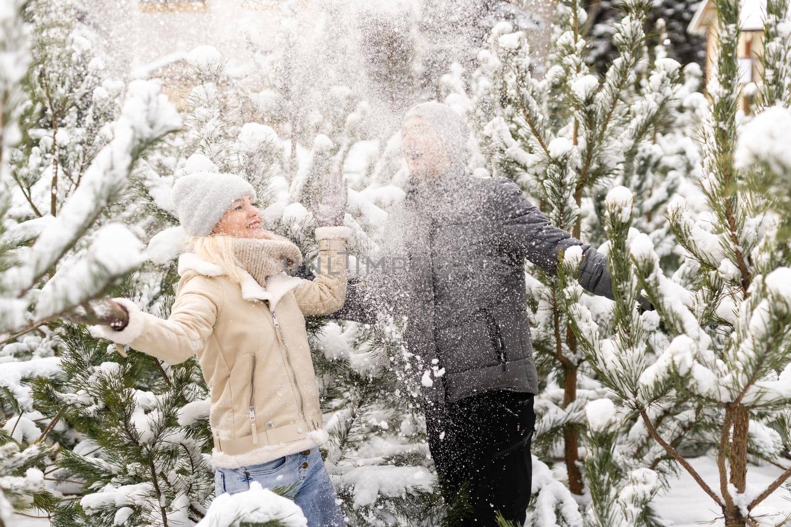 Loving couple cuddles in the winter forest among snowy pines