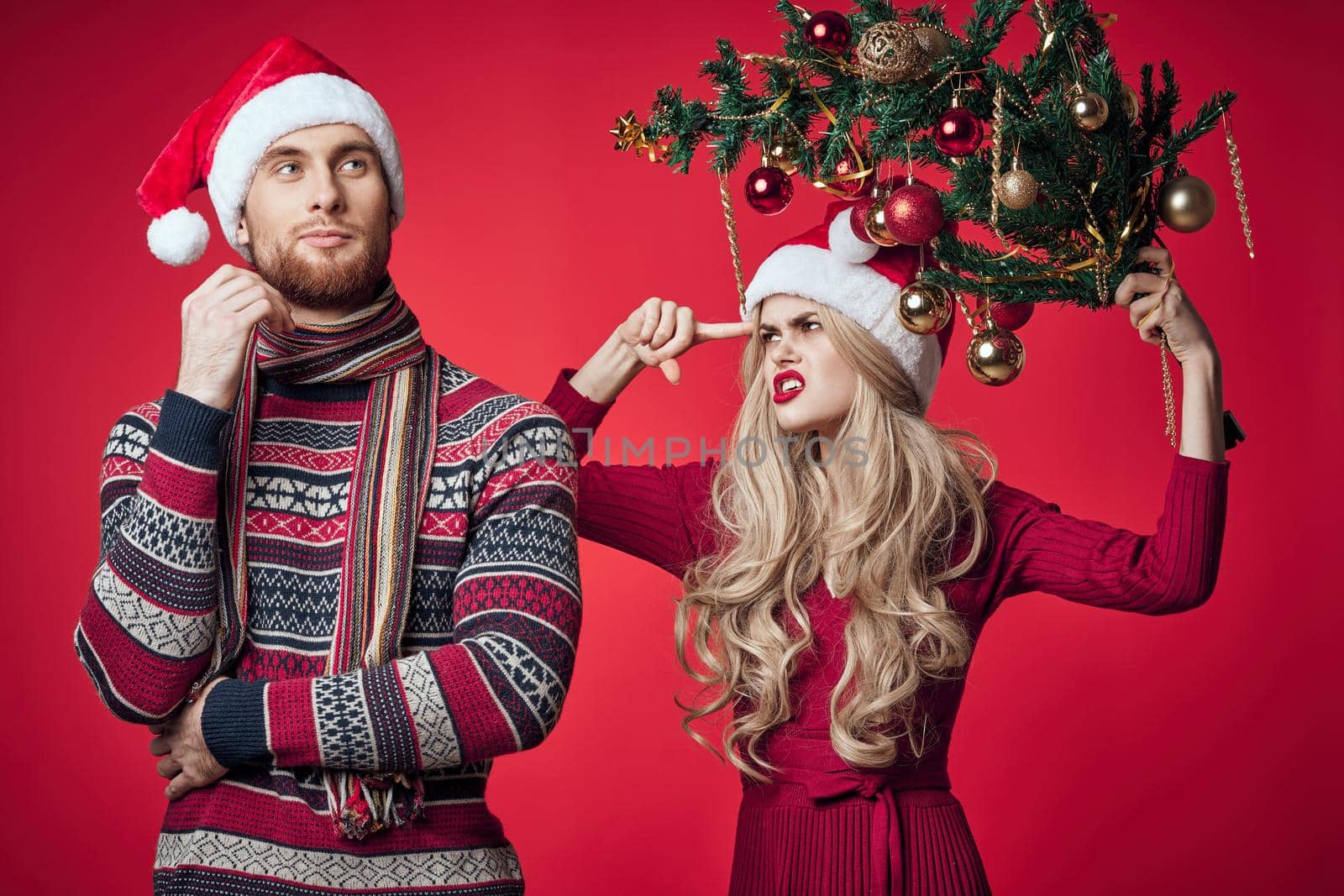 cheerful young couple Christmas tree toys holiday red background. High quality photo