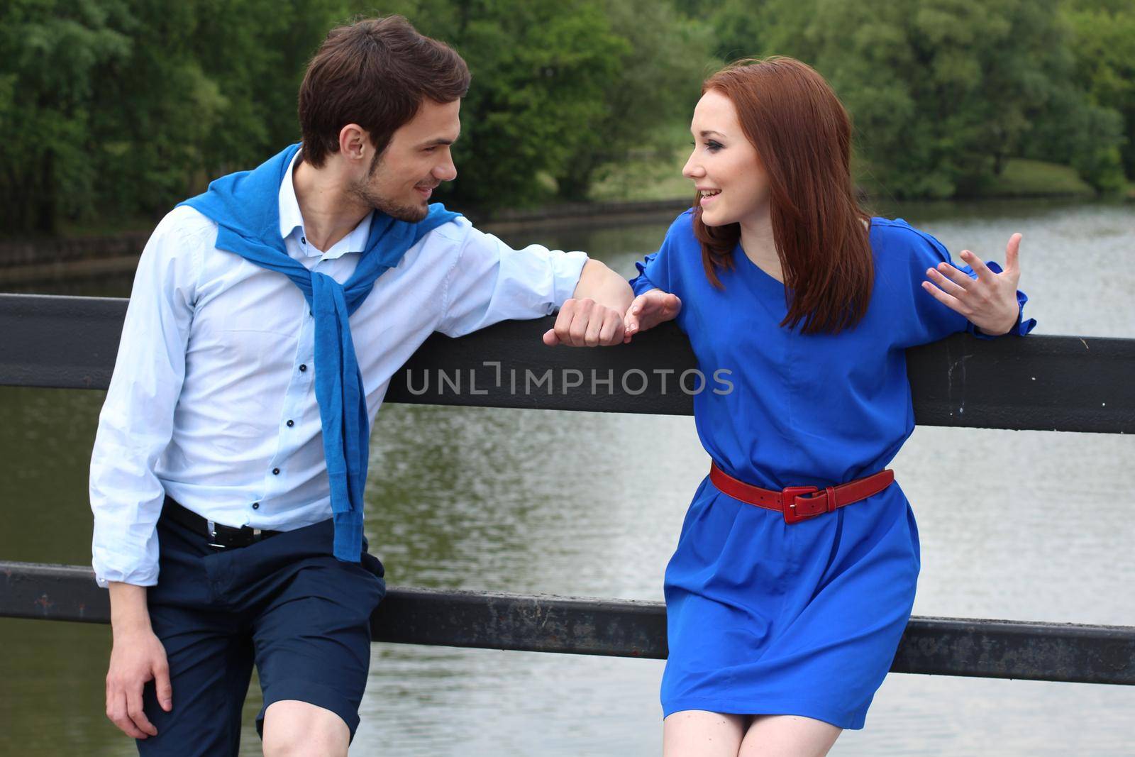 Happy couple meeting near river and greeting each other. Joyful man and woman standing outdoors, hugging and talking. Lovely meeting concept