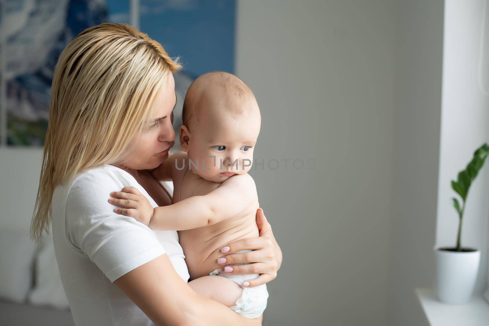 A young mother is holding her newborn baby. Mother of a nursing baby. Mother breastfeeding her baby. The family is at home. Portrait of a happy mother and child.