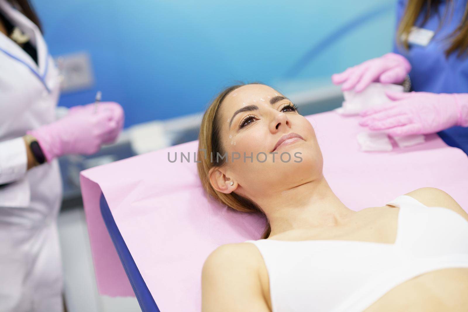 Middle-aged woman lying on the stretcher in an aesthetic clinic. by javiindy