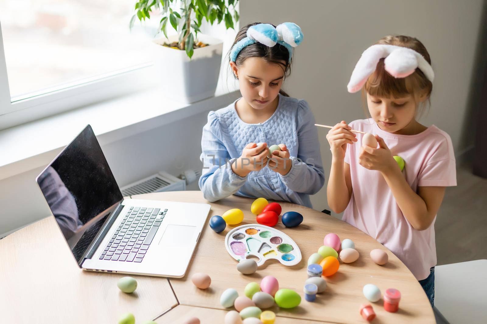 two little girls with ears hold eggs - Easter symbols. Easter egg