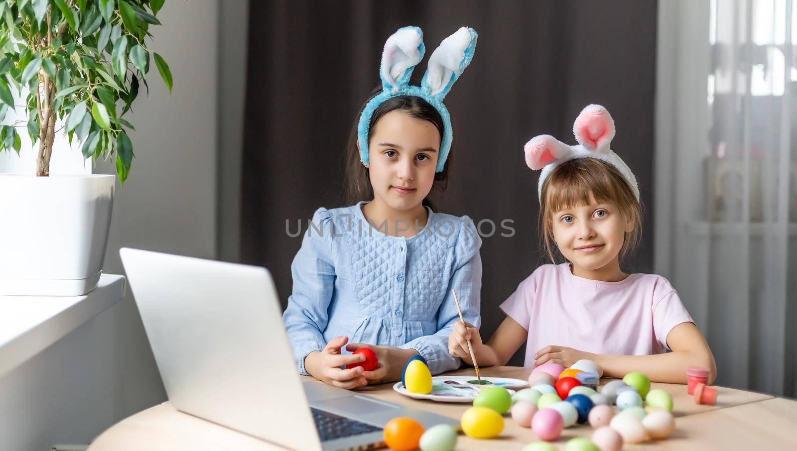 two little girls with ears hold eggs - Easter symbols. Easter egg