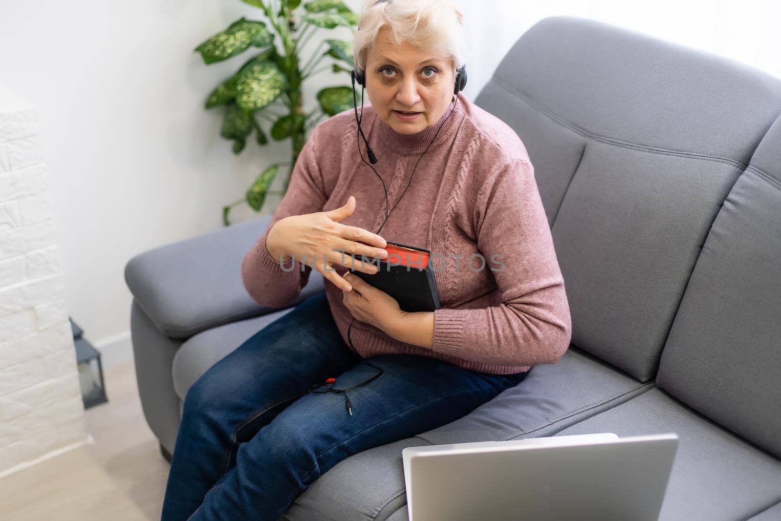 Woman with bible and laptop in front of her connected to online church services durring the covid 19 outbreak