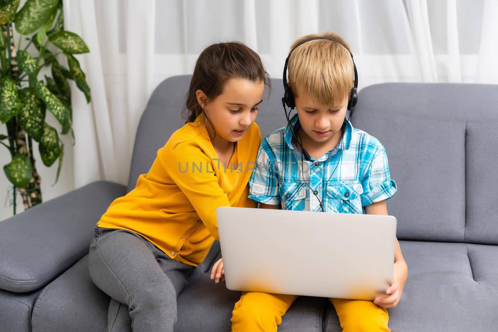 Kids playing with laptop computer at home.