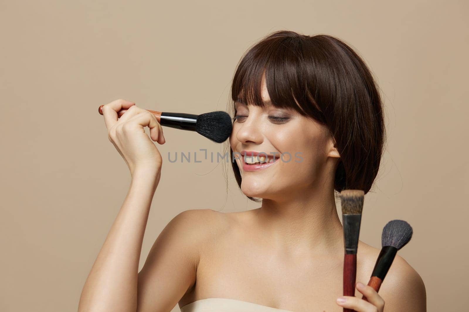 beautiful woman makeup brushes near the face bare shoulders cropped view. High quality photo