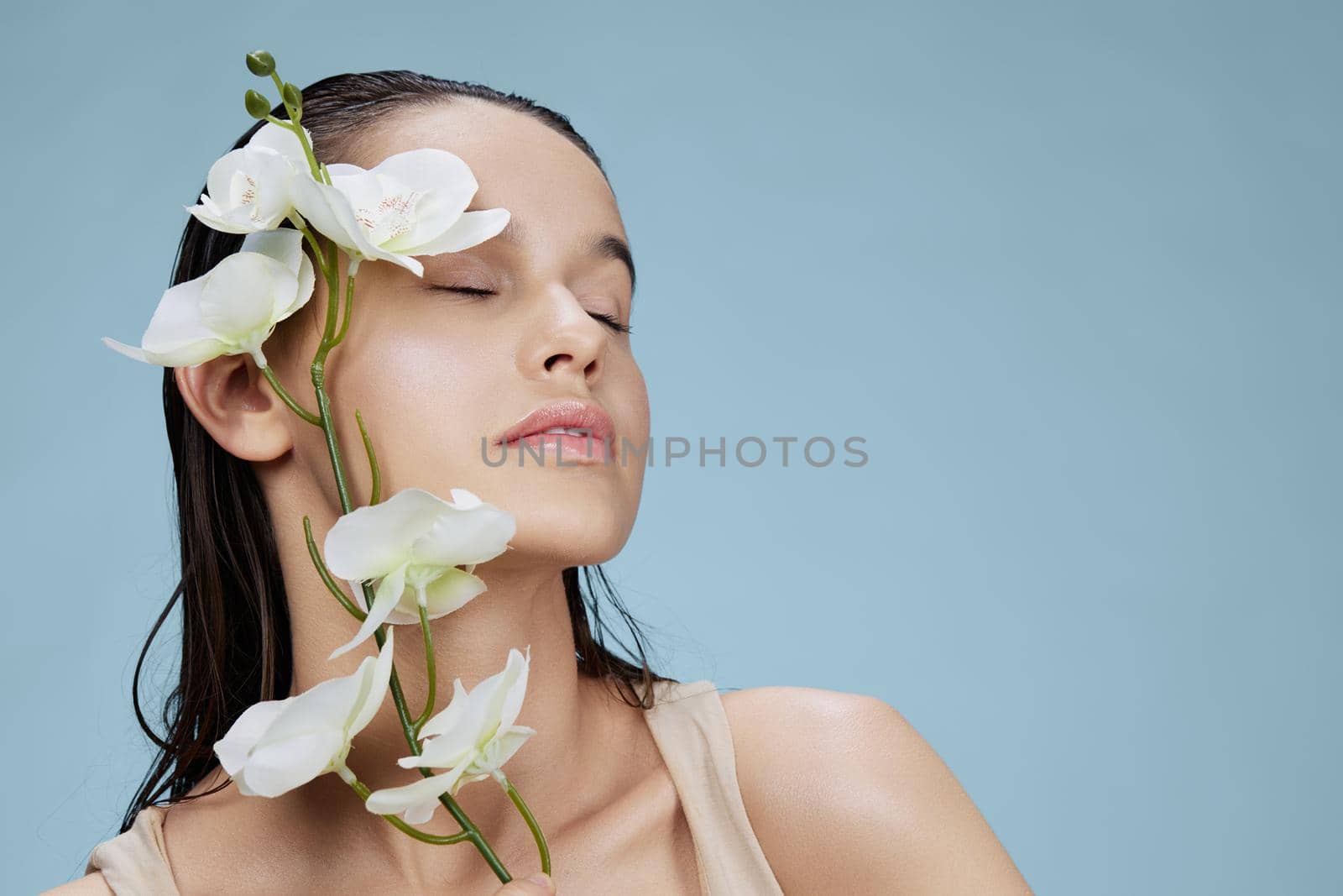 woman orchid flower near face attractive look blue background. High quality photo