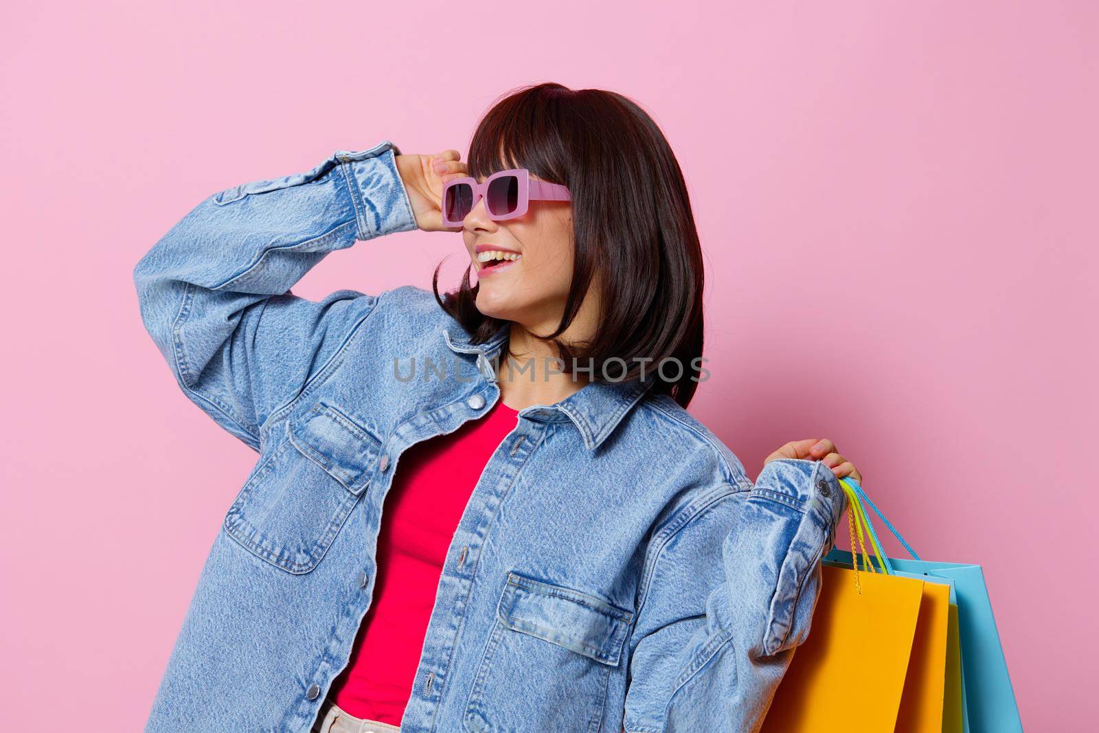 beautiful woman in denim jackets with colorful shopping bags isolated background by SHOTPRIME