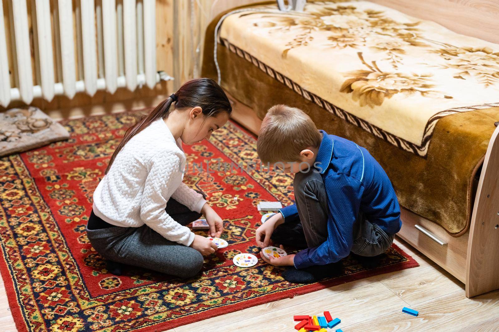 Children playing with blocks on the floor - focus on the boy's face by Andelov13