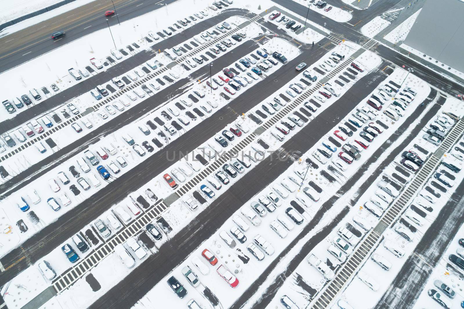 aerial view of a lot of cars in a parking lot and many are covered in snow