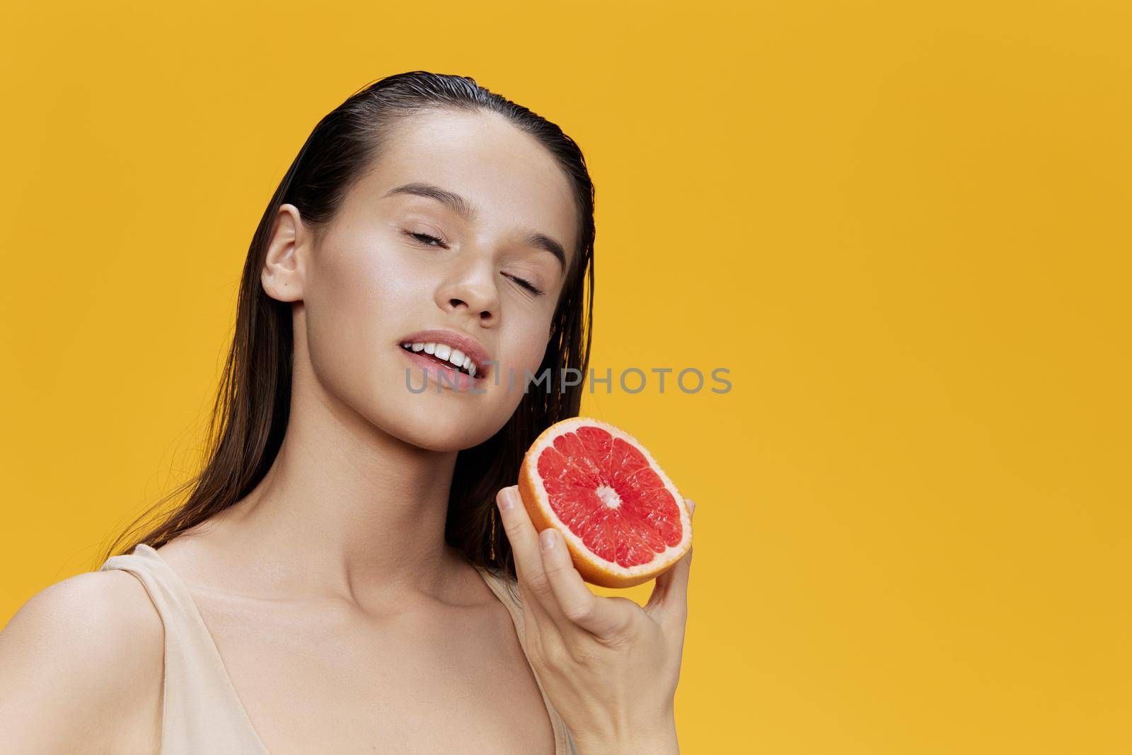 brunette eating grapefruit in hands smile vitamins diet isolated background. High quality photo