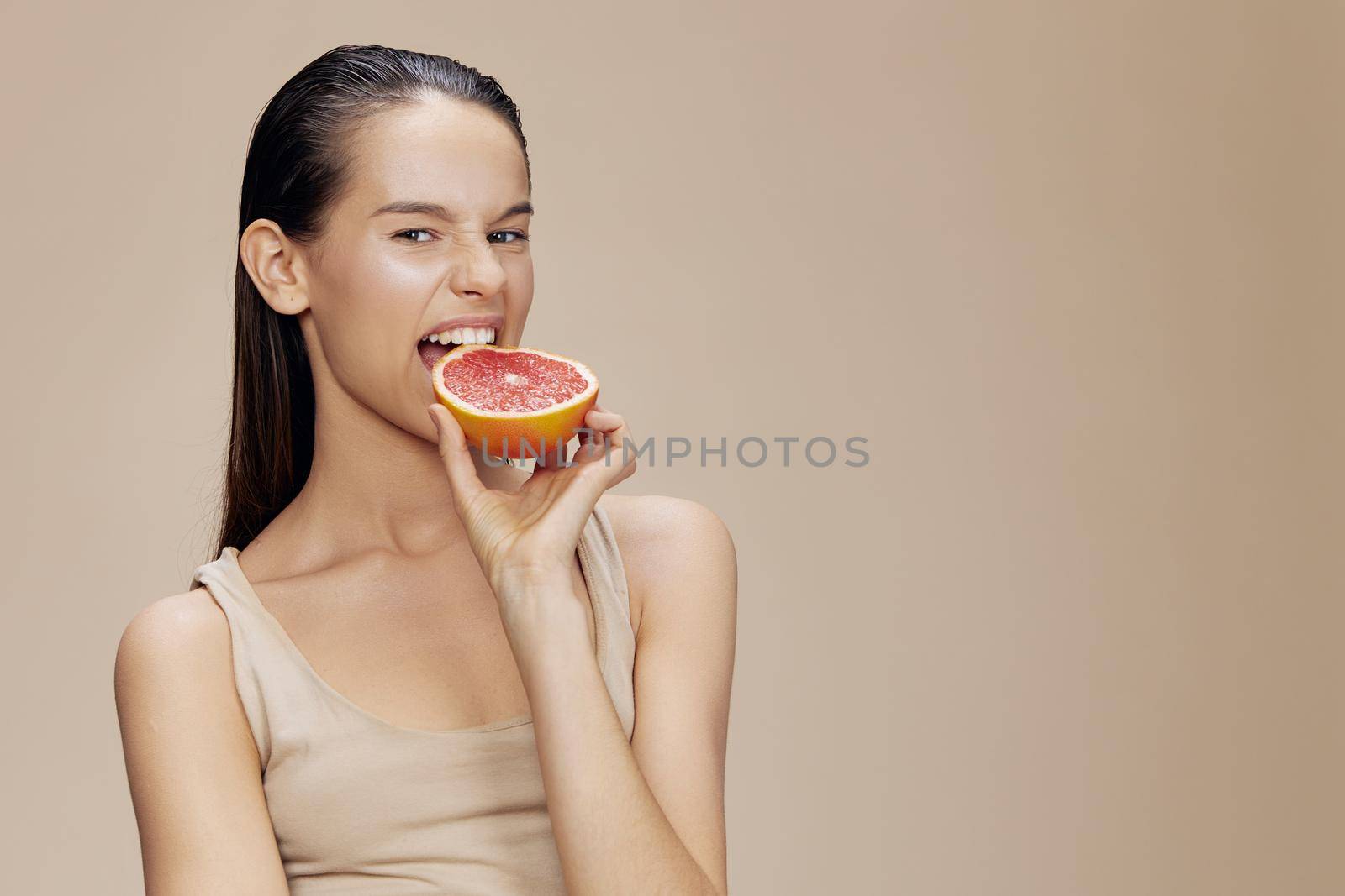 brunette grapefruit in hands posing clean skin beige background by SHOTPRIME