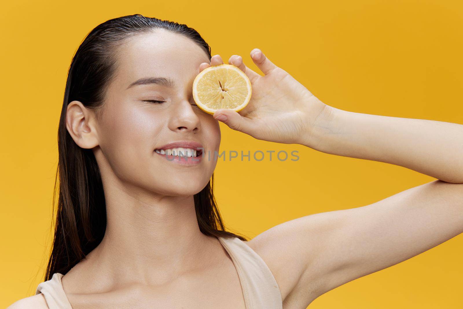 woman with lemon near face clean skin care health yellow background. High quality photo