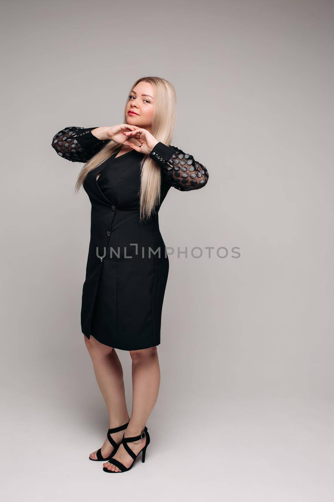 handsome caucasian female with long blonde hair posing to the camera in black dress