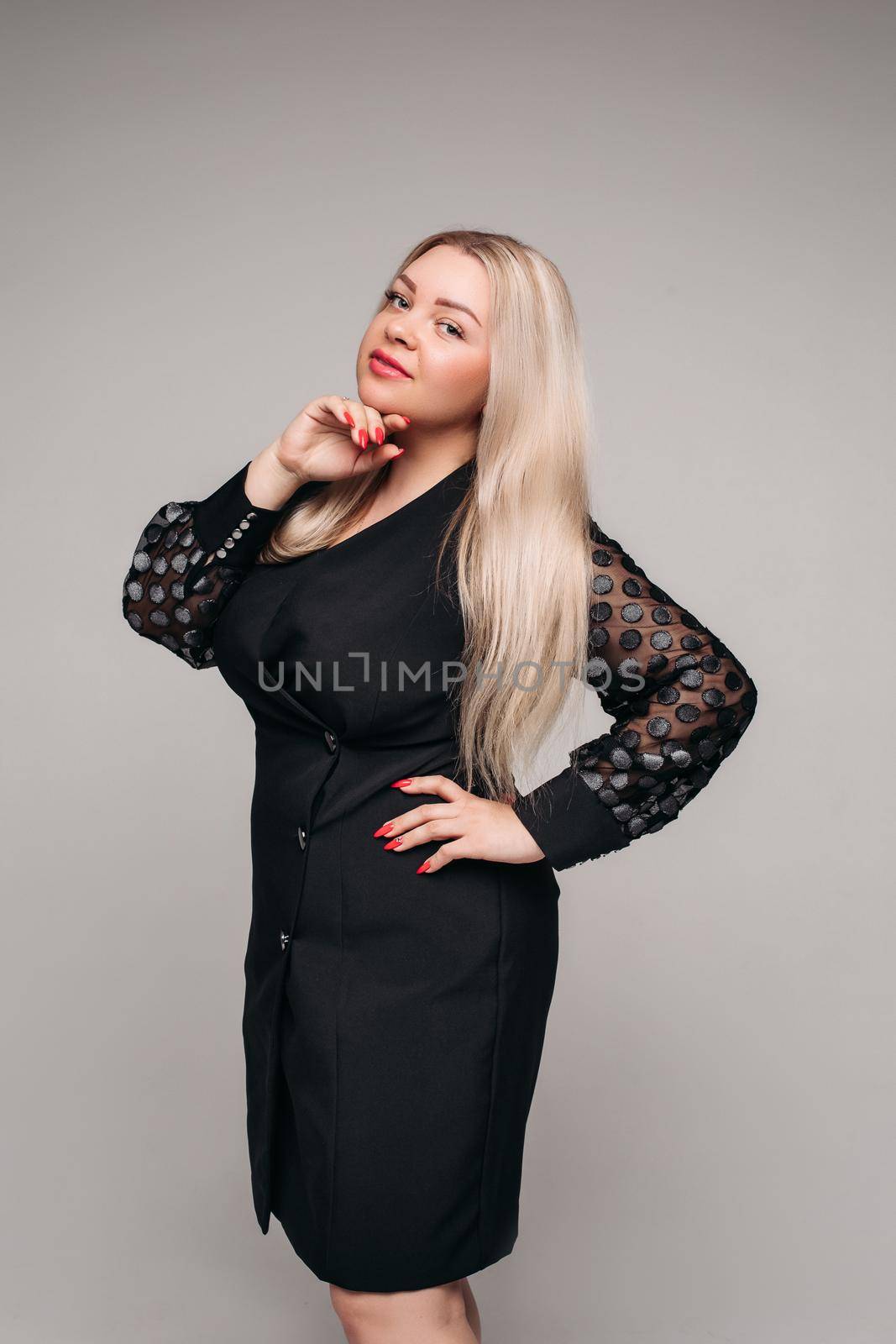 attractive woman with long blonde hair in black dress smiling on white background by StudioLucky