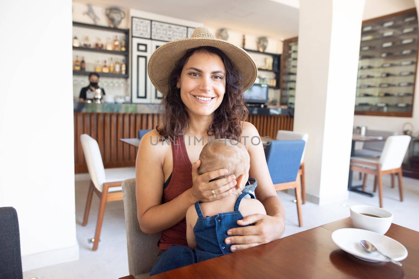 Beautiful smiling mother holding cute baby in restaurant by Kanelbulle