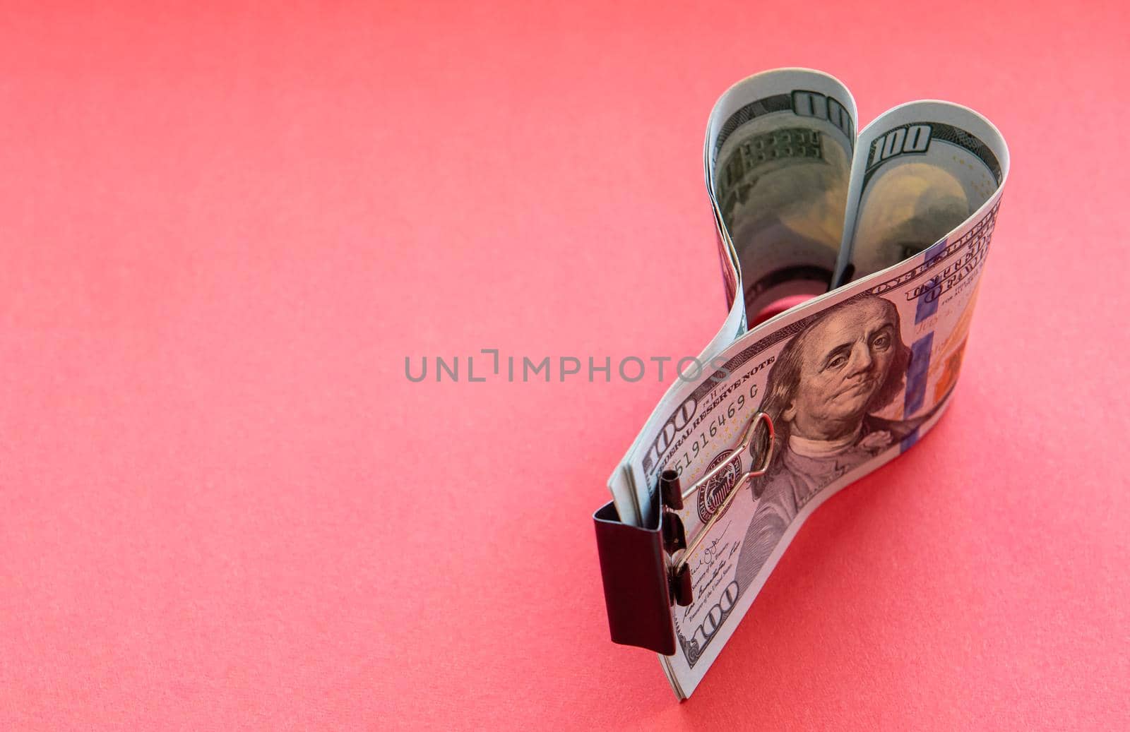 Heart made of dollar bills on a red background by karpovkottt