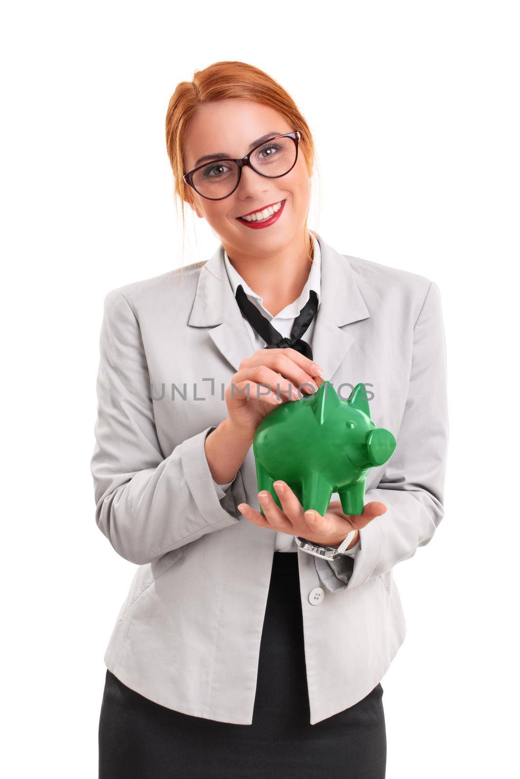 Young smiling businesswoman inserting a coin in piggy bank, isolated on white background. Finance, savings concept.