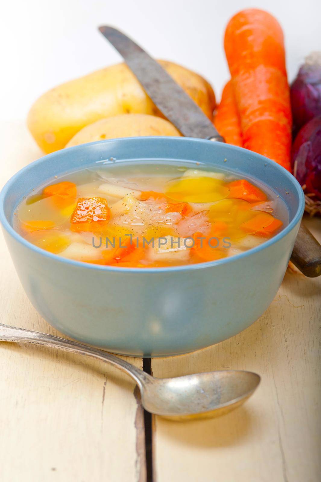 Traditional Italian minestrone soup on a rustic table with ingredients