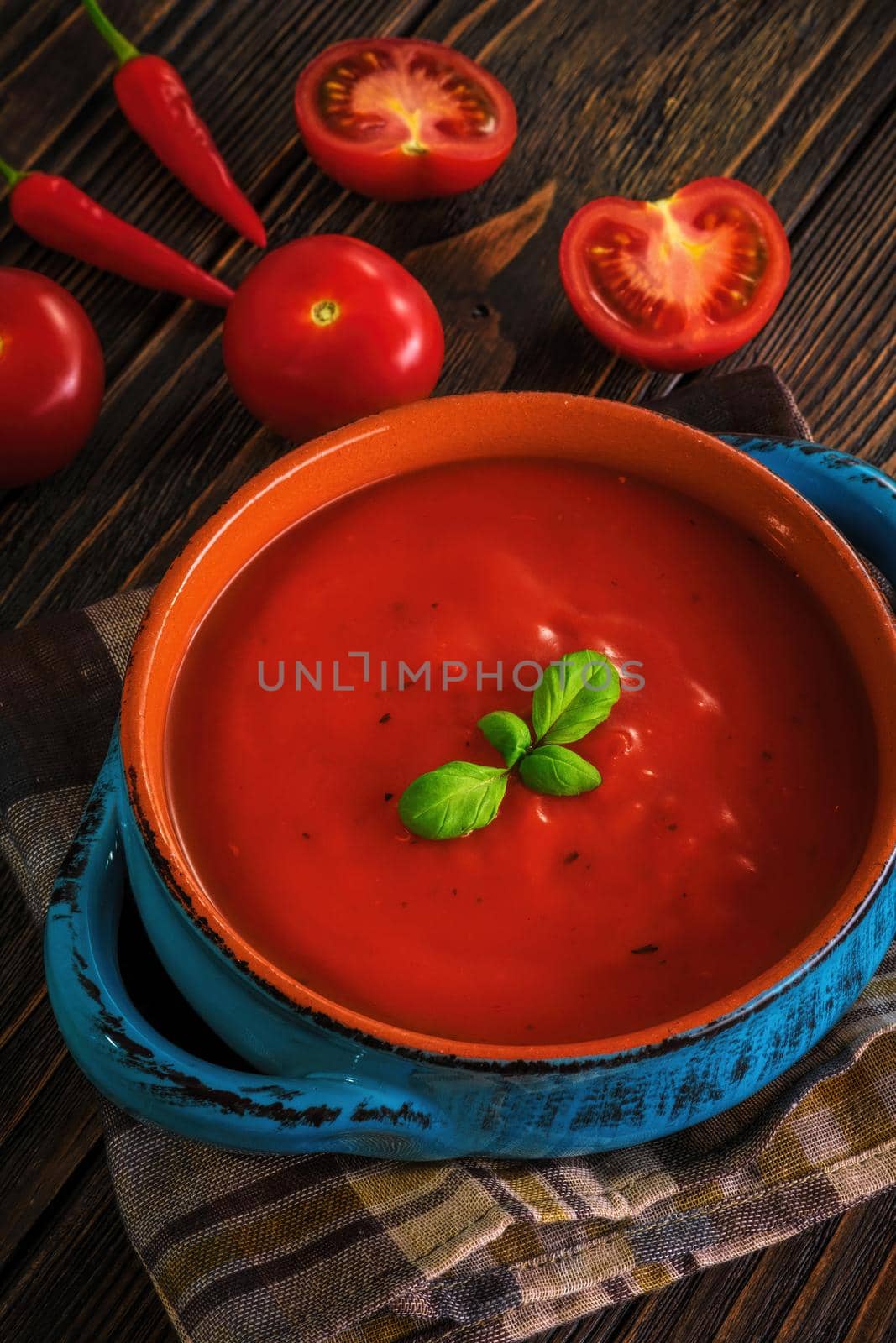 Traditional tomato cream soup and food ingredients on wooden table.