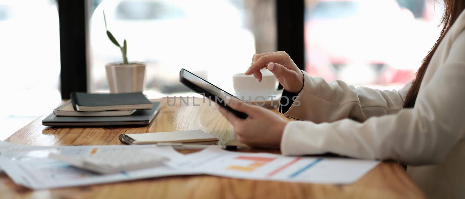 Close-up of female hands using modern digital tablet at office, side view of business woman hands typing text information on touch screen of tablet pc by nateemee