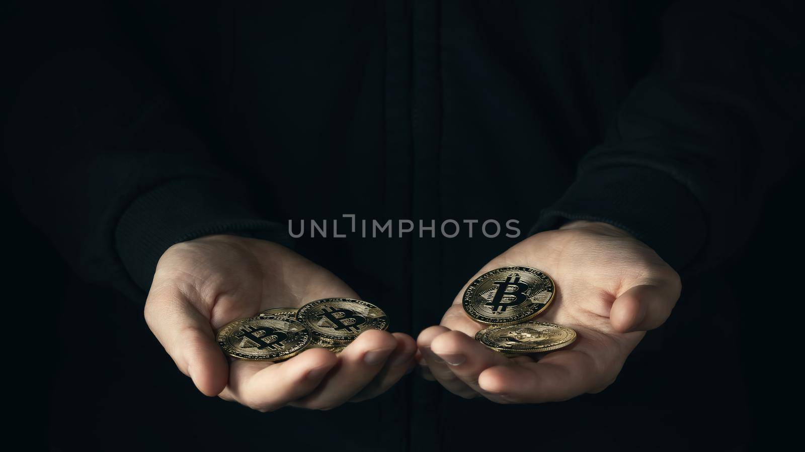 Handful of bitcoins in male palmson a dark background. Financial savings, accumulation in cryptocurrency concept. Selective focus.