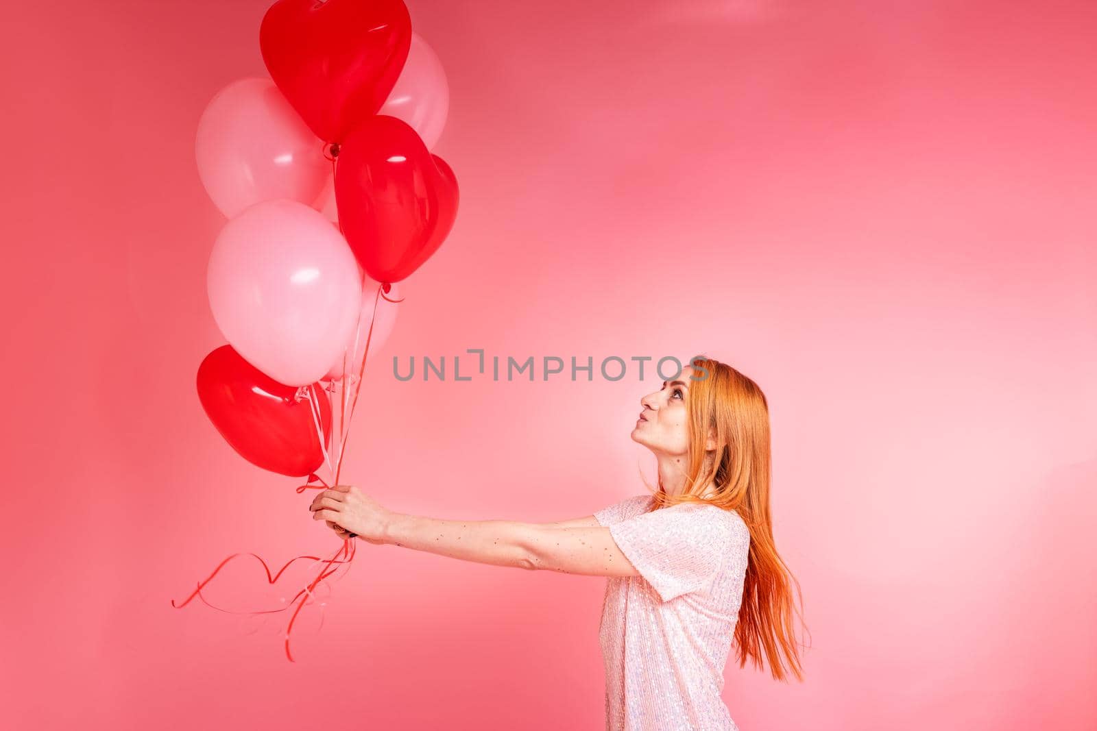 Beautiful redhead girl with red heart baloon posing. Happy Valentine's Day concept by Len44ik