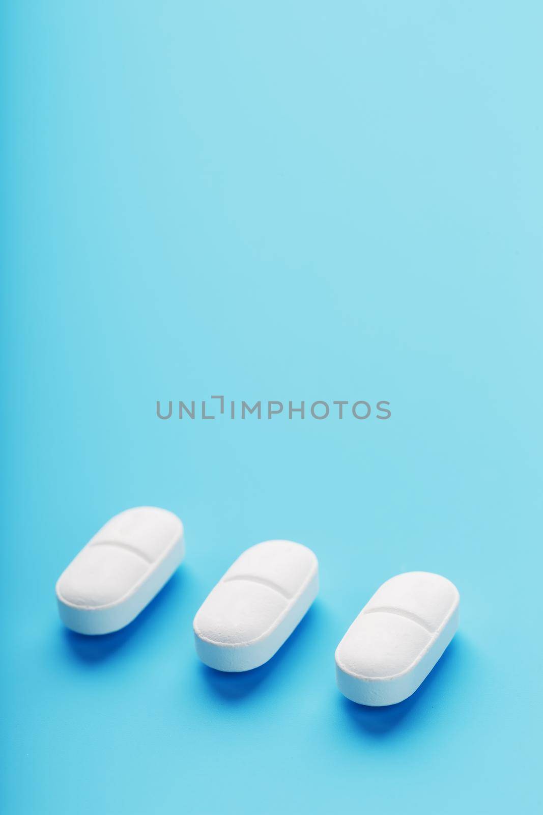 Three medicinal tablets in a row on a blue background, isolate. the view from the top, place for text.